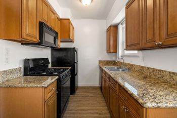 A kitchen with granite countertops and wooden cabinets.